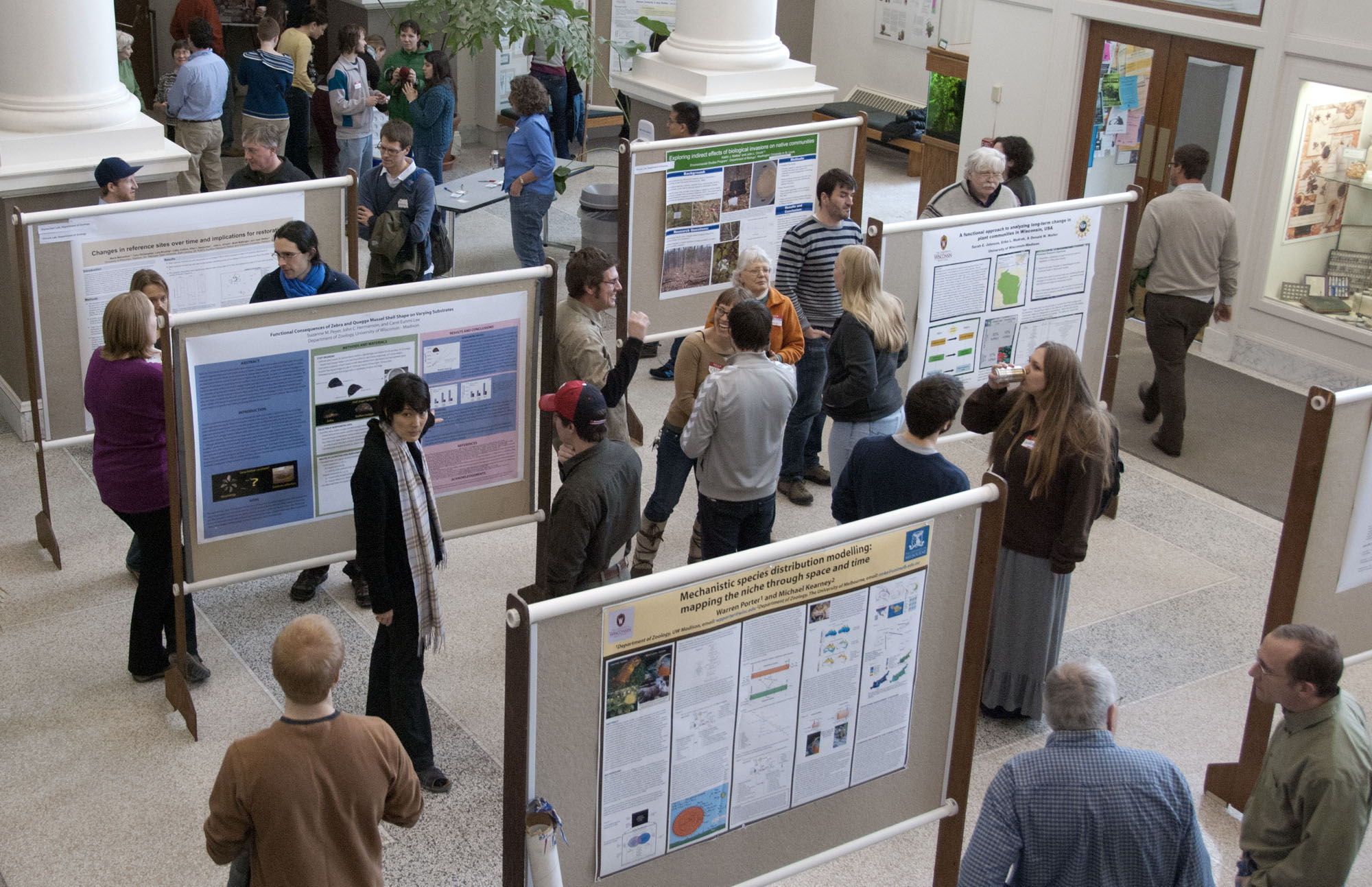 People walk around a room filled with posters on rolling bulletin boards.